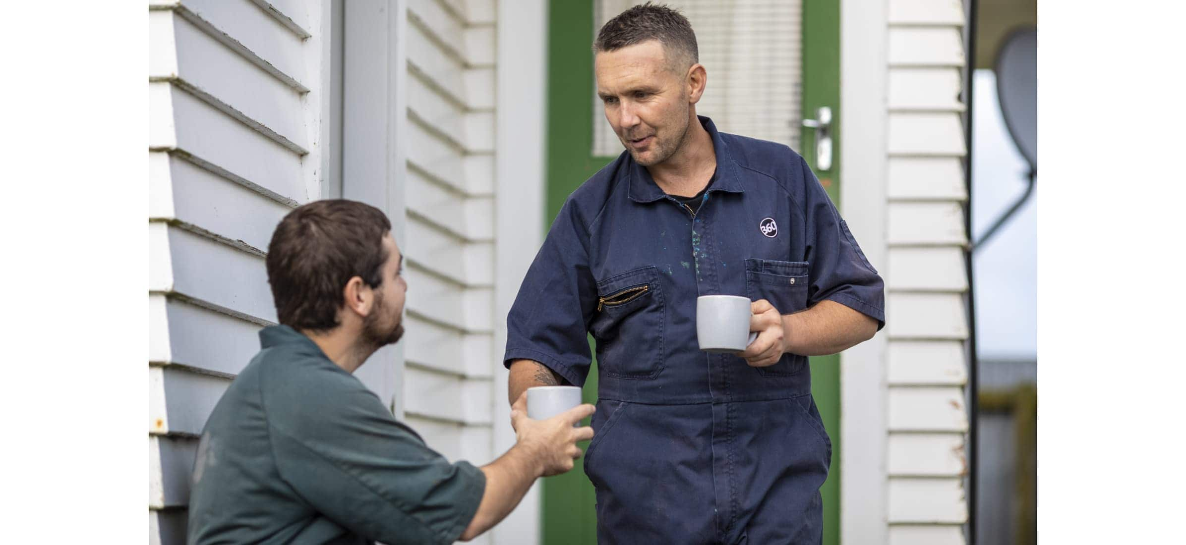 Simon hands employee Tomas a cup of tea outside a home.